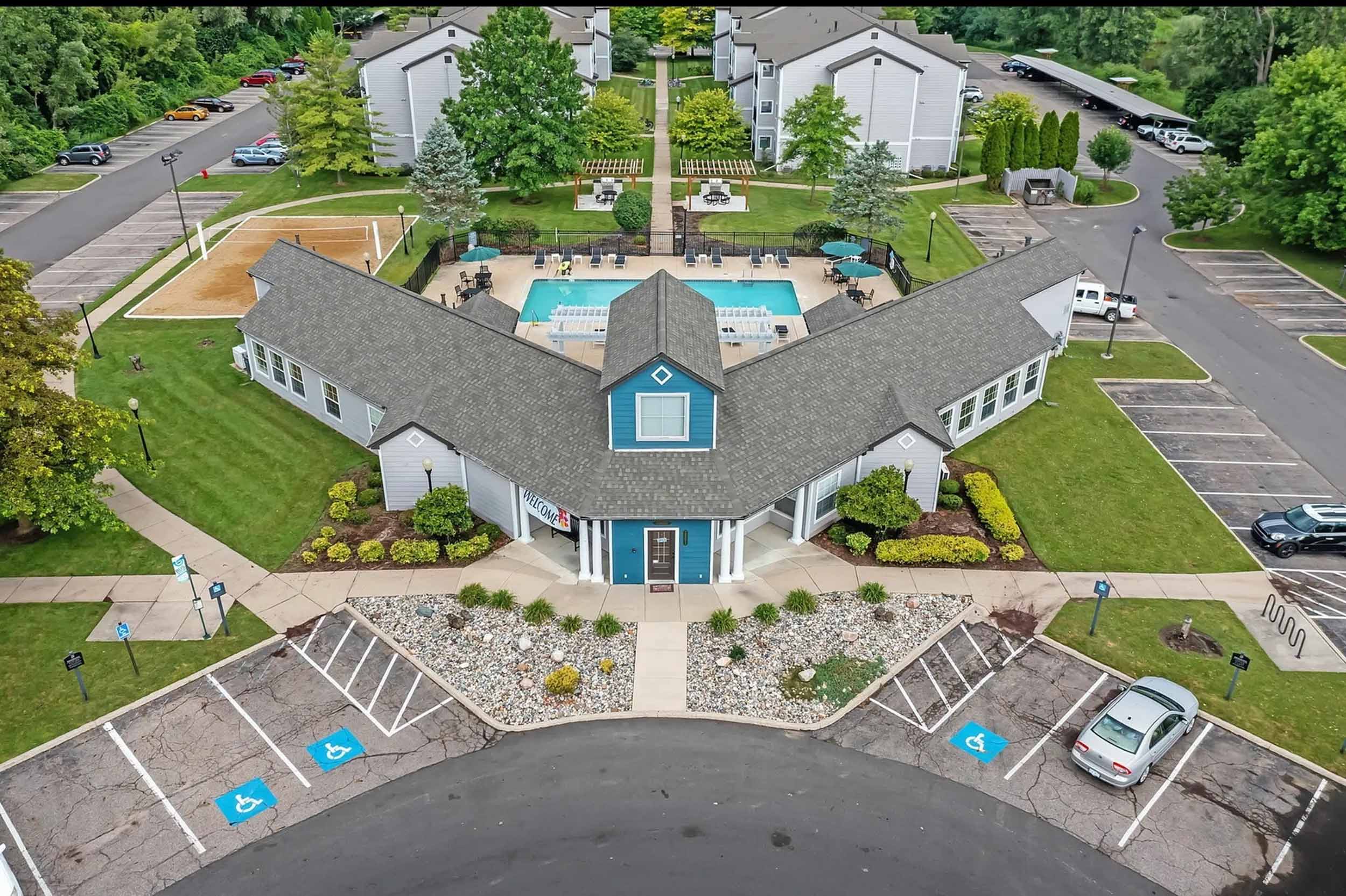 Aerial view of 25 East apartment complex with green spaces parking and a pool courtyard